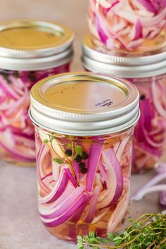 four jars filled with pickled onions and herbs