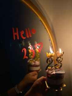 someone is holding a cake with candles in front of the mirror that says hello 25