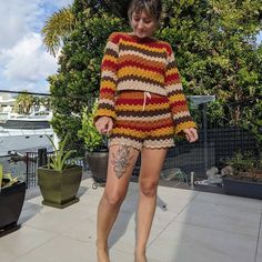 a woman walking on the sidewalk wearing a colorful sweater and matching heels with her legs crossed