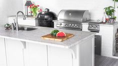 an outdoor kitchen with stainless steel appliances and watermelon cutting board