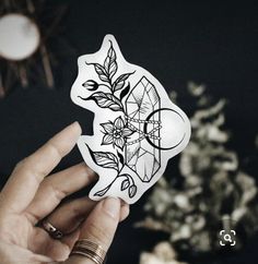 a person holding up a sticker with flowers on it