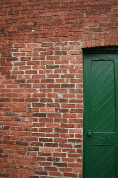 a brick wall with a green door and a stop sign on the side of it