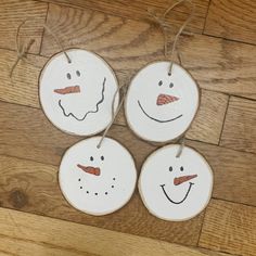 four snowmen ornaments hanging from string on wooden floor with wood planks in the background