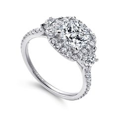 a cushion cut diamond engagement ring with halos on the shoulders and sides, set in 18k white gold