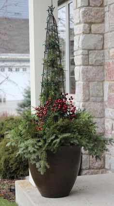 a potted plant with berries and greenery in it on the front step of a house