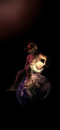 an astronaut is sitting on top of the earth in outer space, holding a glowing light