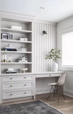 a white desk sitting in front of a window next to a chair and bookshelf