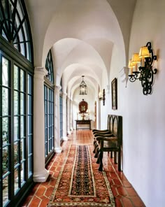 the hallway is lined with arched windows and rugs