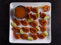 a white plate topped with shrimp and celery next to a dipping sauce