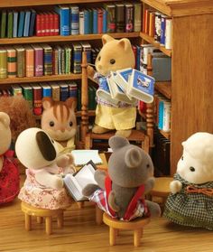 several stuffed animals sitting in front of a bookshelf