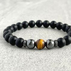 Men's beaded bracelet made with strong, stretchy cord and genuine/natural gemstones. Features ~ 6mm, 8mm or 10mm Matte Onyx beads ~ 6mm, 8mm or 10mm Yellow Tiger Eye bead ~ 6mm, 8mm or 10mm Hematite round beads ~ 4mm, 6mm or 8mm Hematite spacer beads ~ Stretchy cord; simply slide bracelet on and off wrist ~ Comes packaged in a re-usable microfiber pouch To ensure the perfect fit, please use the bracelet sizing instructions found in the photo gallery. Onyx - A powerful protection stone, Black Ony Blue Tiger Eye, Slide Bracelet, Blue Tiger, Blue Tigers, Blue Tigers Eye, Tiger Eye Beads, Mens Beaded Bracelets, Onyx Bead, Beaded Stretch Bracelet