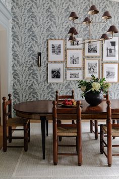 a dining room table with chairs and pictures on the wall