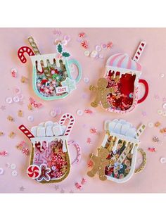 three christmas ornaments are sitting on a pink surface with confetti, candy and candies