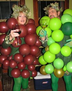 two people dressed in green and red holding wine glasses