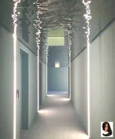 an empty hallway with white walls and lights on the ceiling