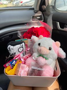 a stuffed pig sitting in the back seat of a car filled with flowers and gifts