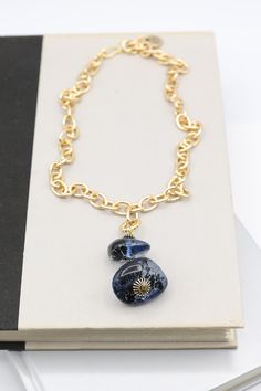 This elegant necklace features two ocean blue resin beads on a gold-plated chain. The light-catching surface of the beads offers an additional hint of luxury to the wearer. With its timeless design and luxurious materials, it's the perfect accessory to any outfit.Details: Gold Chain Necklace Drop Feature with Two Blue Resin Beads Approximate Dimensions: Length: 18.0" Drop Feature Length: 2.75" Small Blue Bead: 1.0" x 0.4" Large Blue Bead: 1.25" x 0.5" Elegant Blue Delicate Chain Necklace, Elegant Blue Beaded Chain Necklace, Elegant Blue Clavicle Chain Necklace, Blue Gold-plated Chain Necklace As Gift, Blue Gold Plated Chain Necklace As Gift, Elegant Blue Metal Chain Necklace, Blue Adjustable Gold-plated Chain Necklace, Blue Gold-plated Chain Necklace With Adjustable Chain, Blue Adjustable Gold Plated Chain Necklace