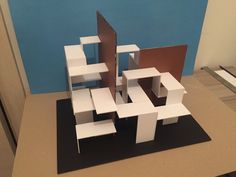 the model is made out of cardboard and sits on a table next to a blue wall