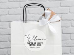 a white paper bag with a welcome message on it and a ribbon tied around the handle