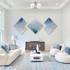 a living room with white furniture and blue accents