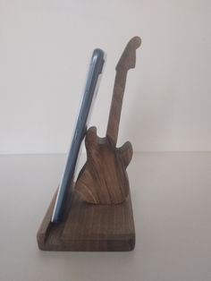 a wooden guitar shaped pen holder with a cell phone in it