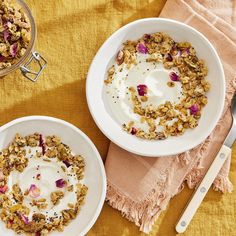 two bowls filled with granola and yogurt on top of a yellow cloth