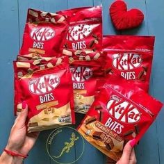 a person holding five bags of krispy kreme bites next to a red heart