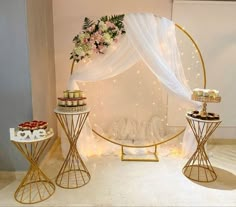 a table topped with cakes and cupcakes under a white drape