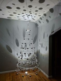 a christmas tree made out of balls and lights in a room with wood flooring