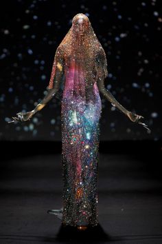 a woman in a long dress with stars all over her body and hands out to the side