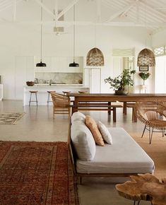 a living room filled with furniture next to a kitchen and dining room table on top of a rug