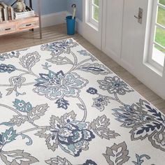 a white rug with blue and green flowers on it in front of a door way