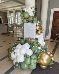 a table topped with balloons and greenery in front of a sign that says welcome