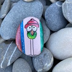 a rock painted with an image of a bird wearing a hat on top of some rocks