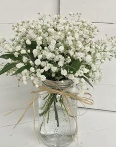 a mason jar filled with baby's breath flowers on a white wooden table top