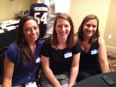 three women sitting next to each other in front of a table