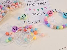 two bracelets with smiley faces on them sitting next to a sign that says make your own bracelet