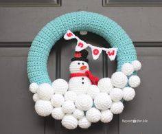 a crocheted snowman wreath is hanging on the front door