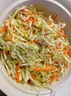 a white bowl filled with coleslaw and carrots on top of a table