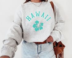 a woman wearing a sweatshirt with the word hawaii printed on it and a green shamrock