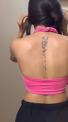 the back of a woman's neck with a flower tattoo on her lower back