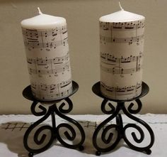 two white candles with musical notes on them