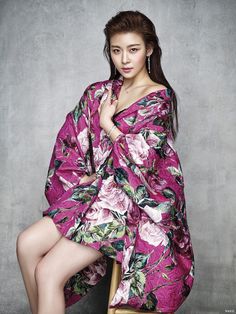 a woman sitting on top of a chair wearing a pink flowered kimono over her body