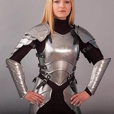 a woman dressed in armor poses for a photo with her hands on her hips and arms behind her back