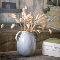 there is a vase with some flowers in it on the table next to a book