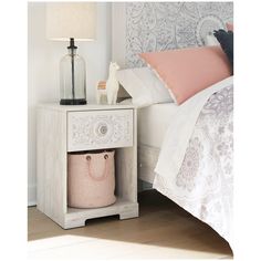 a bedroom with a bed, nightstand and lamp on the side table in front of it