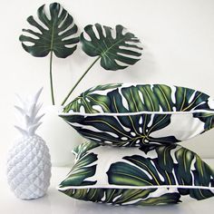 two decorative pillows with green leaves and a white pineapple