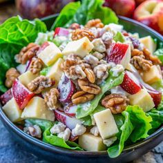 a salad with apples, walnuts and cheese in a bowl on a blue surface