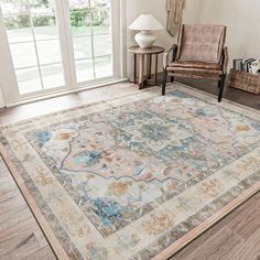 a living room area with a chair and rug on the floor, windows to the outside