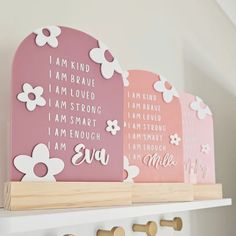 three pink and white wooden plaques with flowers on them, one saying i am kind of brave